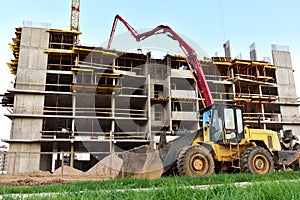 Formworks and pouring concrete through a oncrete pump truck connected to a ready-mixed truck. Wheel loader at construction site. photo