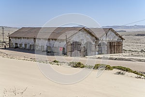 forsaken warehouse buildings on sand at mining ghost town in desert, Kolmanskop, Namibia