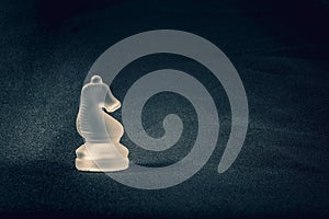 Forsted white glass knight chess piece on dramatic background