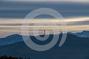 Forstsee - Panoramic scenic view of the viewing tower Pyramidenkogel and the snow capped Karawanks