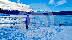 Forstsee - Rear view of man with hiking backpack watching the frozen lake Forstsee, Techelsberg, Carinthia (Kaernten), Austria,