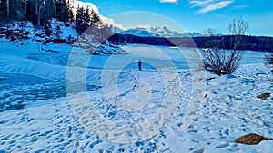 Forstsee - Rear view of man with hiking backpack watching the frozen lake Forstsee, Techelsberg, Carinthia (Kaernten), Austria,