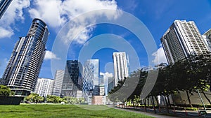 Fort Bonifacio skyline. Verdant green fields of an empty lot in front. Modern office buildings and condos in back