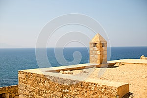 Fort castle with a tower from pirimindalnoy roof high above the azure sea