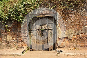 An ancient rustic wooden door on an old, laterite brick wall in the heritage town of
