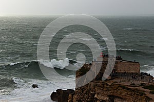 Fort of Sao Miguel Arcanjo Lighthouse in Nazare, Portugal. Big Waves on Cloudy Day photo