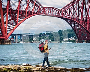 Forth Bridge, Scotland. Active middle-aged woman with a backpack looking at the Forth Railway Bridge Edinburgh.UK, Europe. Concept