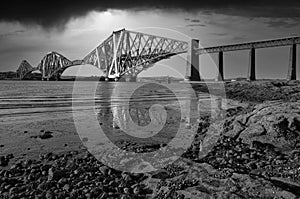 The Forth Rail Bridge captured in the sunlight prior to a storm, black and white.