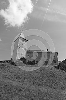 Fortified medieval church in Europe from the bottom of the hill in black and white.