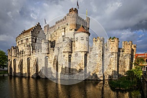 Fortified walls and towers of Gravensteen medieval castle with moat in the foreground, Ghent East Flanders, Belgium