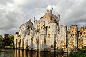 Fortified walls and towers of Gravensteen medieval castle with moat in the foreground, Ghent East Flanders, Belgium