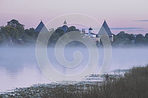Fortress in the city of Staraya Ladoga on the Volkhov River with a foggy pink summer dawn