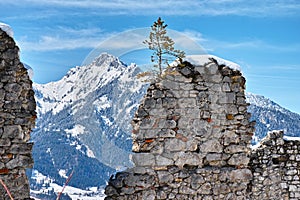 Ruined wall of medieval castle in alpine winter landscape