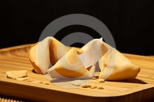 Fortune cookies with blank paper inside on a bamboo board with black background