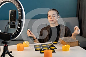 Fortune teller blogger with tarot cards to prediction future uses ring lamp and smartphone. Astrologist influencer