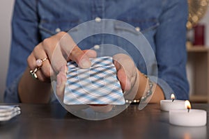 Fortune teller with deck of tarot cards at grey table indoors, closeup