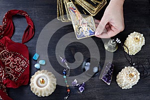 Fortune teller female hands and tarot cards on dark wooden table. Divination concept.