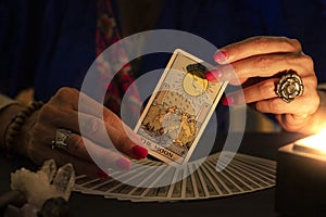 Fortune teller hands showing The moon tarot card. Close-up with candle light, moody atmosphere