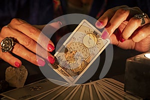 Fortune teller hands showing The moon tarot card. Close-up with candle light, moody atmosphere