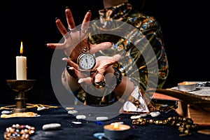 The fortune teller holds a watch on a chain in her hands and conjures over it. The concept of divination, astrology and predicting photo