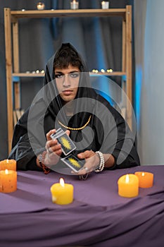 Fortune teller magical man reading future on tarot cards. Ritual candles burning, seance, smoke.