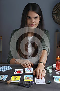 Fortune teller predicting future on spread of tarot cards at grey table indoors