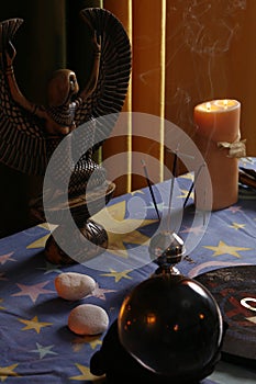 Fortune teller`s table with crystal ball, incense, candles and other occult objects