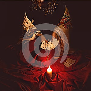 Fortune teller sees in the future by playing her tarot cards in dark burning candle