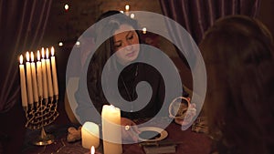 Fortune teller woman in dark room with lots of candles Gives an explaination of future and prediction of fate to a
