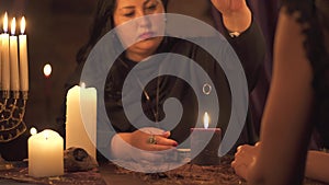 Fortune teller woman in dark room with lots of candles Gives an explaination of future and prediction of fate to a