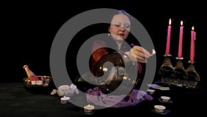 A fortuneteller in a magic salon lights candles on a black background