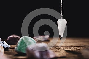 Fortunetelling and horoscope with a pendulum and healing gemstones, black background