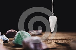 Fortunetelling and horoscope with a pendulum and healing gemstones, black background photo