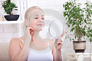Forty years old woman looking at wrinkles in mirror. Plastic surgery and collagen injections. Makeup. Macro face. Selective focus