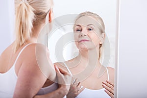 Forty years old woman looking at wrinkles in mirror. Plastic surgery and collagen injections. Makeup. Macro face. Selective focus