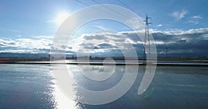 Forward aerial view flooded rice agricultural rural fields with electric line pylon. Daylight sunny summer or spring