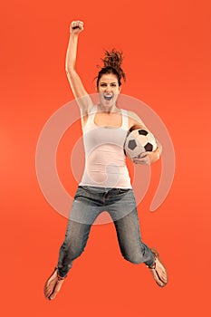 Forward to the victory.The young woman as soccer football player jumping and kicking the ball at studio on a red