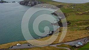 Forwards fly above buildings in countryside near sea coast. Tilt up reveal of peninsula with high cliff. Ireland