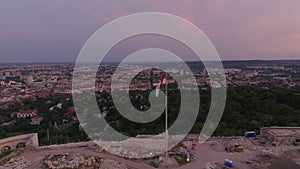 Forwards fly above Citadella fortification on hill above city. Cityscape at twilight. Budapest, Hungary