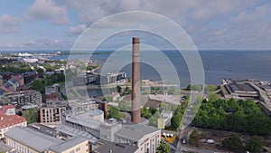 Forwards fly above former power plant, now used as art and science center. Brick factory chimney near sea coast. Tallinn