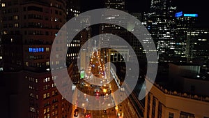 Forwards fly above Market Street in night city. Modern high rise office buildings with lighted windows. San Francisco