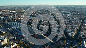 Forwards fly above urban neighbourhood. Large buildings of Atocha train station and traffic in streets around.