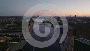 Forwards fly above water canal in evening city. Modern design buildings on waterfronts. Aerial view of capital against