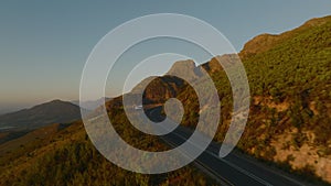 Forwards fly along road in mountains. Travellers standing at lookout point and watching sunset. South Africa