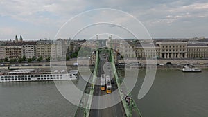 Forwards fly over historic Szabadsag bridge spanning wide Danube river in city. Trams and cars driving on bridge