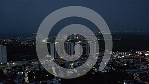 Forwards rising fly above night town. Modern tall apartment buildings in luxury residential complex. Cancun, Mexico