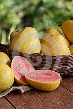 Foto de  fruta de Goiaba cortadas  na cesta em fundo de madeira e blurred garden background photo