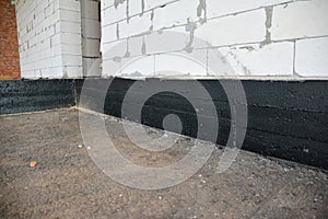 Foundation bitumen waterproofing. Building house construction with waterproofing spray-on tar. Construction techniques for