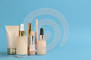 Foundation makeup products on light blue background, space for text. Decorative cosmetics