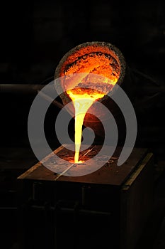 Foundry - molten metal poured from ladle into moul photo